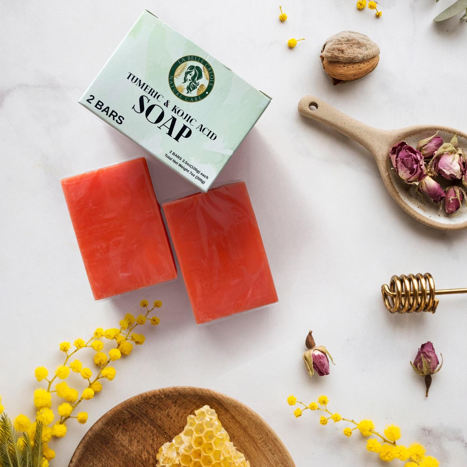 Two red soap bars with a box labeled 'Tomato & Kojic Acid Soap' on a white surface with decorative elements.